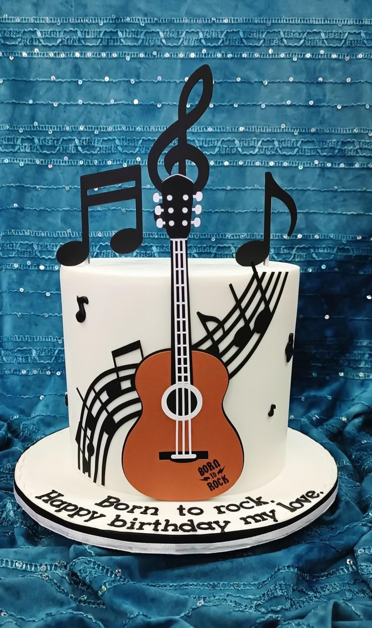 a cake decorated with musical notes and a guitar on it's side, sitting on a blue background