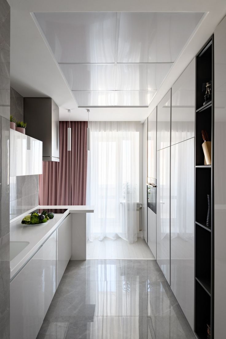 a kitchen with white cabinets and marble flooring next to a window covered in curtains