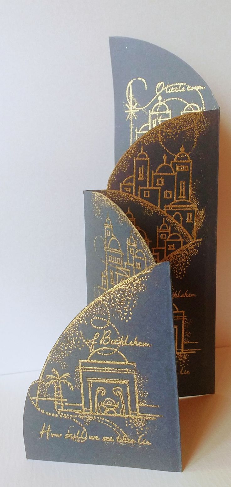 two blue and gold folded cards with an image of a city on them, one in the middle