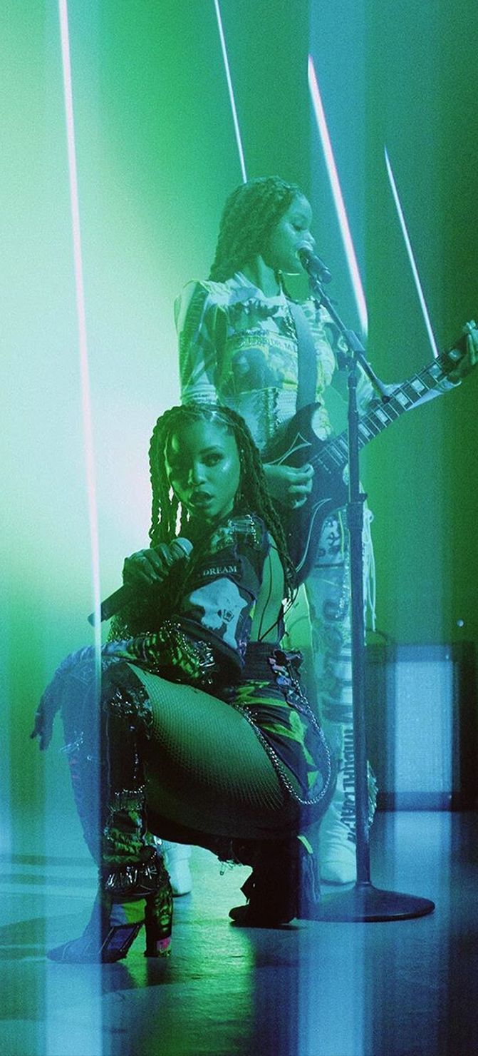 two women sitting on the floor in front of microphones with lights coming from behind them