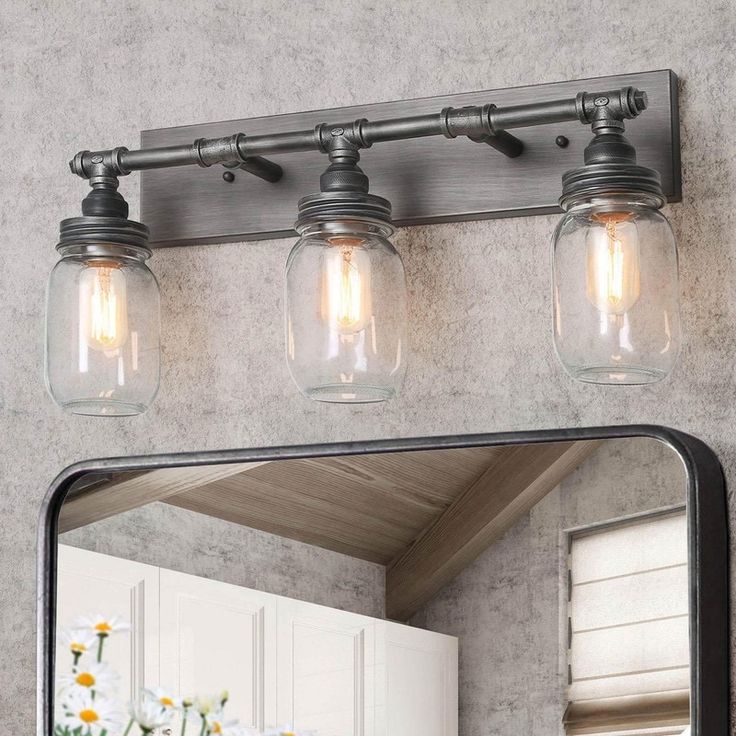 a bathroom vanity light with three mason jars on it