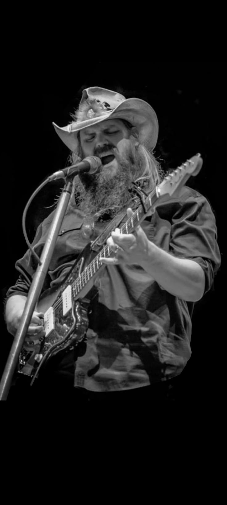 a man with a beard playing guitar and singing into a microphone