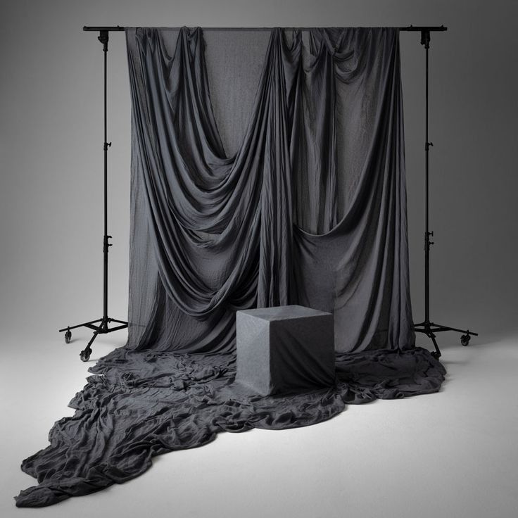 an empty photo studio with black drapes on the walls and grey backdrop in front of it