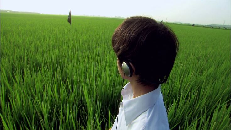 a person with headphones standing in the middle of a field