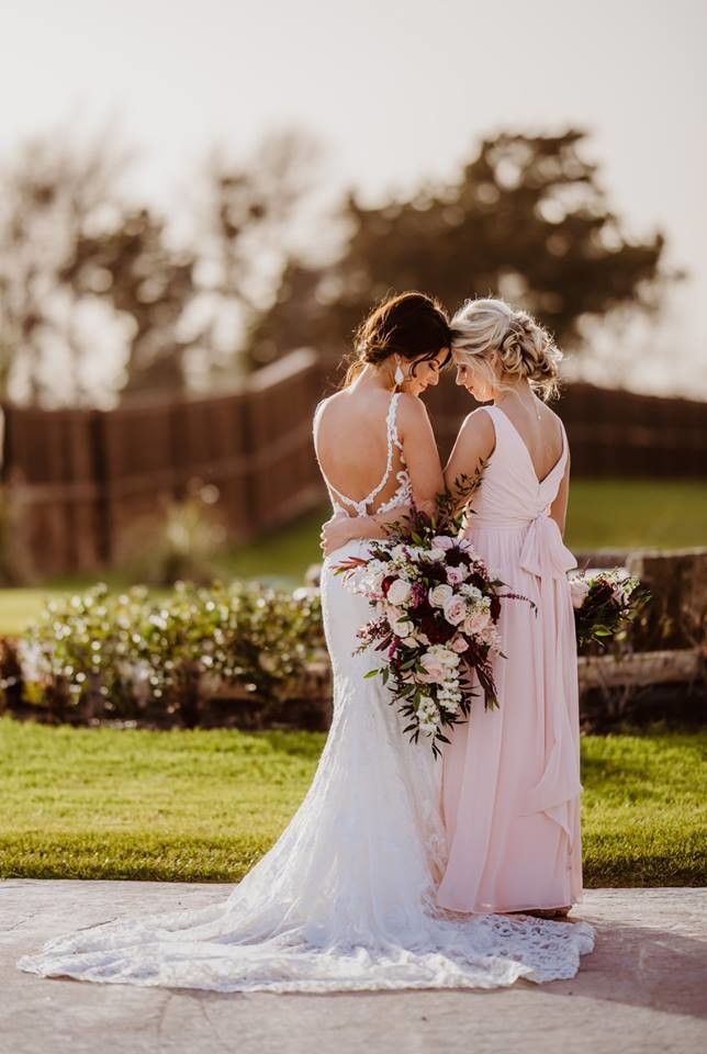 two women in dresses standing next to each other with flowers on their heads and holding bouquets