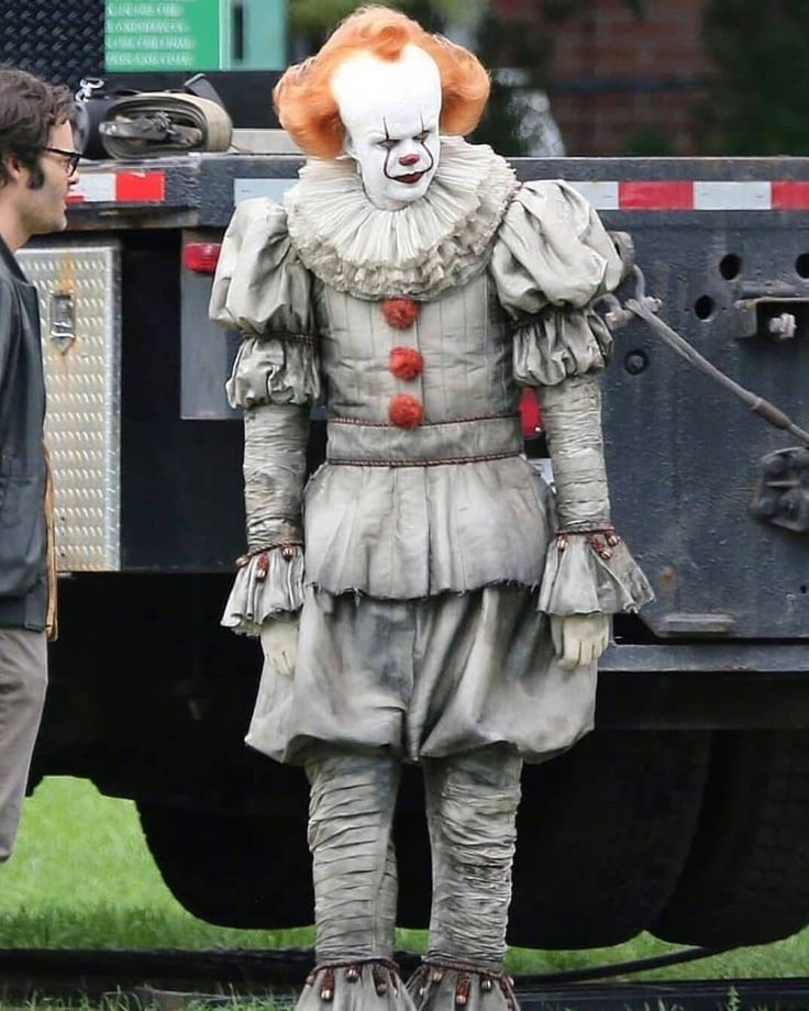 a man in a clown costume standing next to a truck