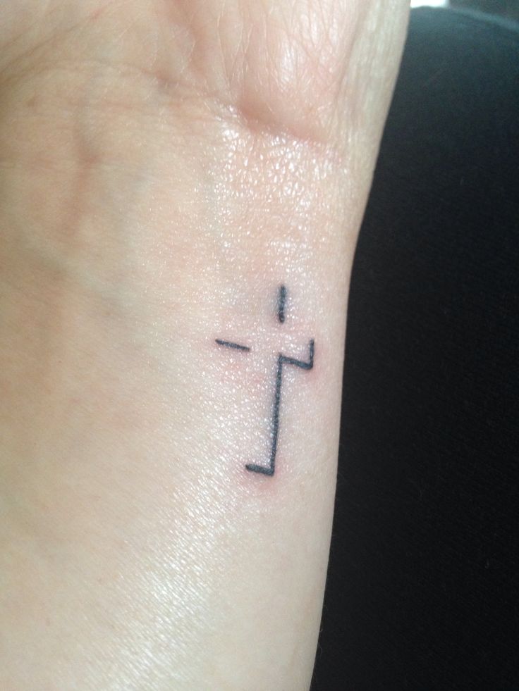 a small cross tattoo on the wrist