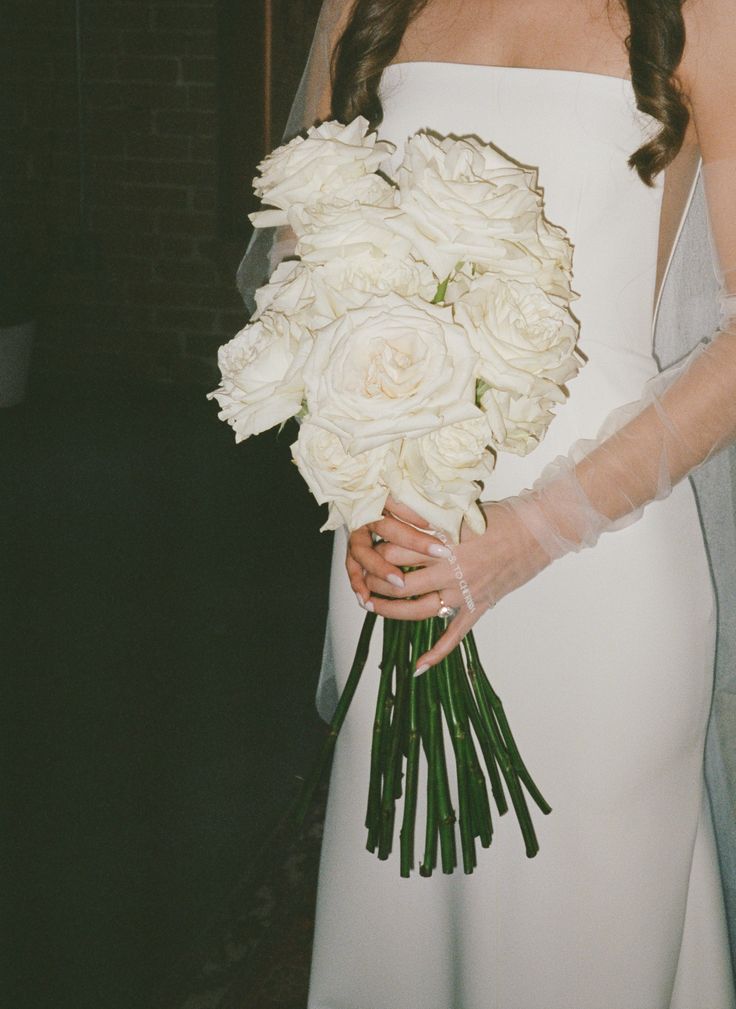 a bride holding a bouquet of white roses