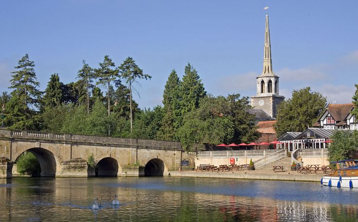 there is a small boat on the water near a bridge and church tower in the background