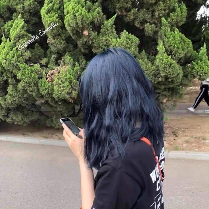 a woman with blue hair is looking at her cell phone