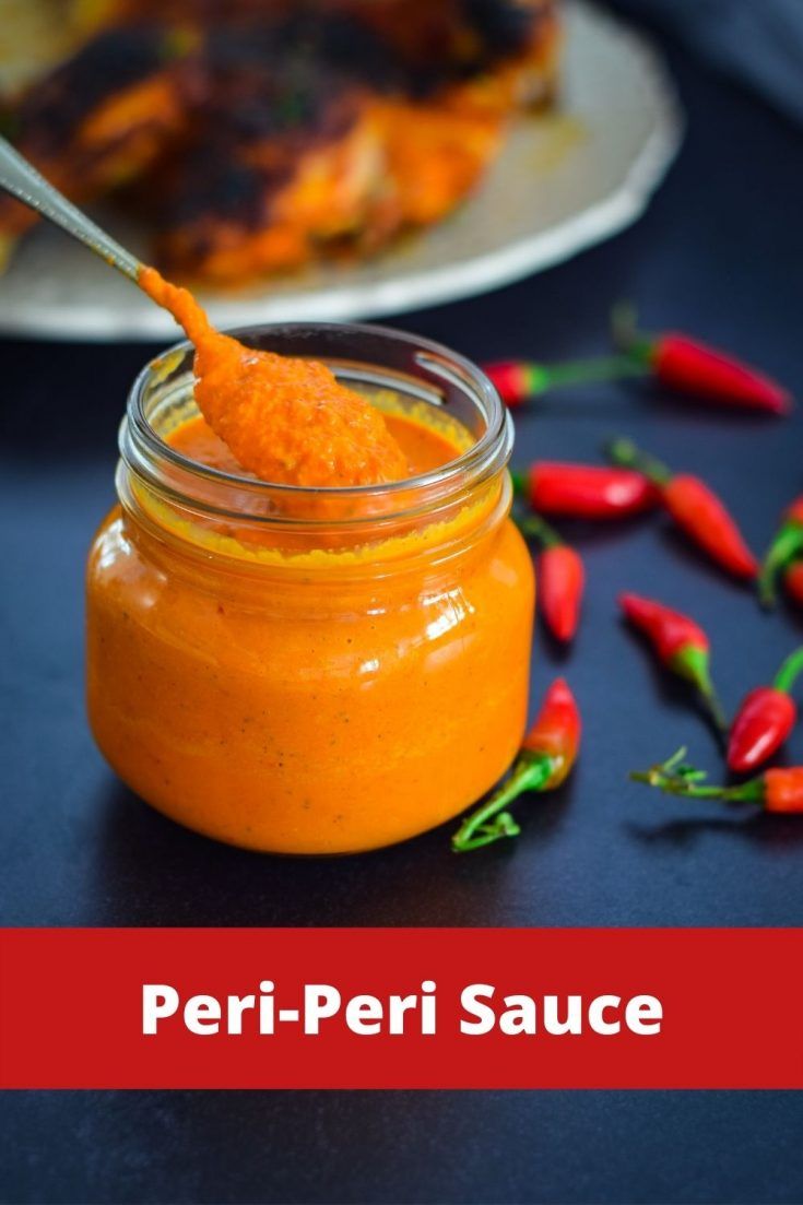 a jar filled with orange sauce next to some chili peppers on a plate and in the background