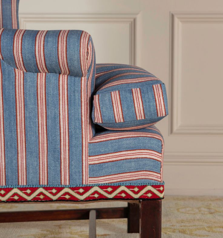 a blue and red striped chair sitting on top of a rug