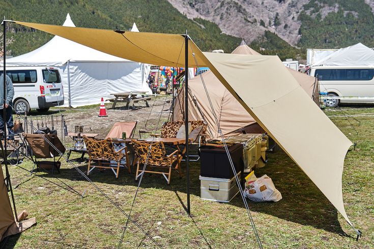 an outdoor tent set up with chairs and tables in front of the mountainside area