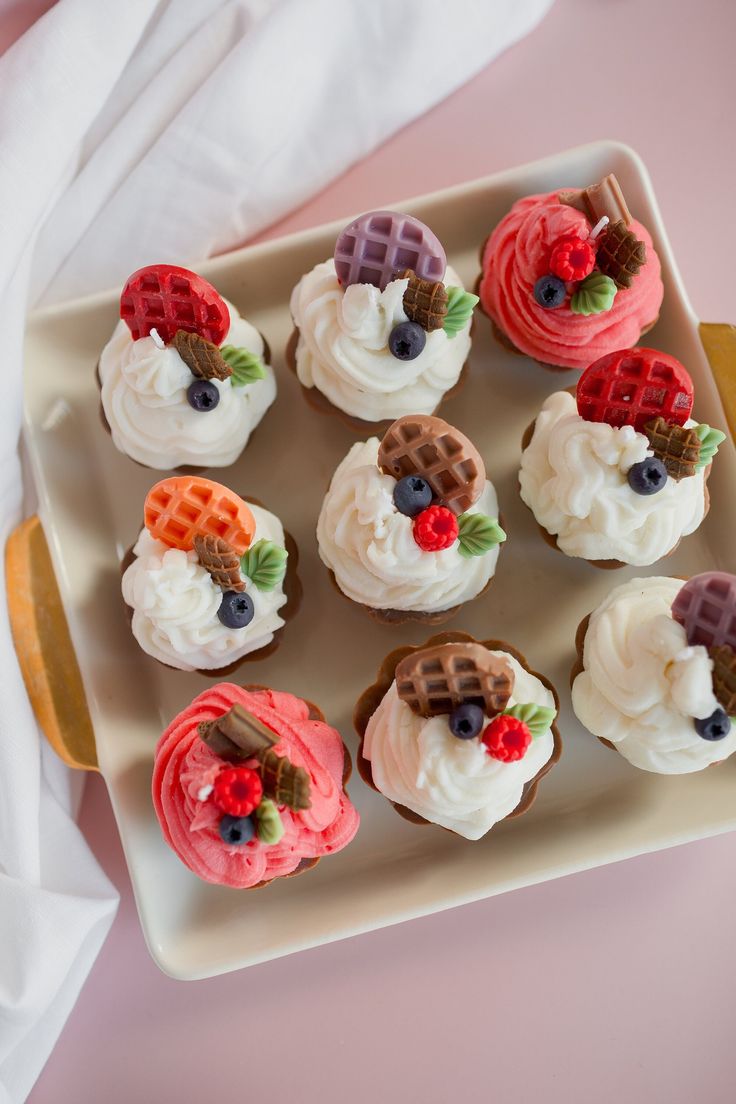 cupcakes with frosting and fruit are arranged on a plate