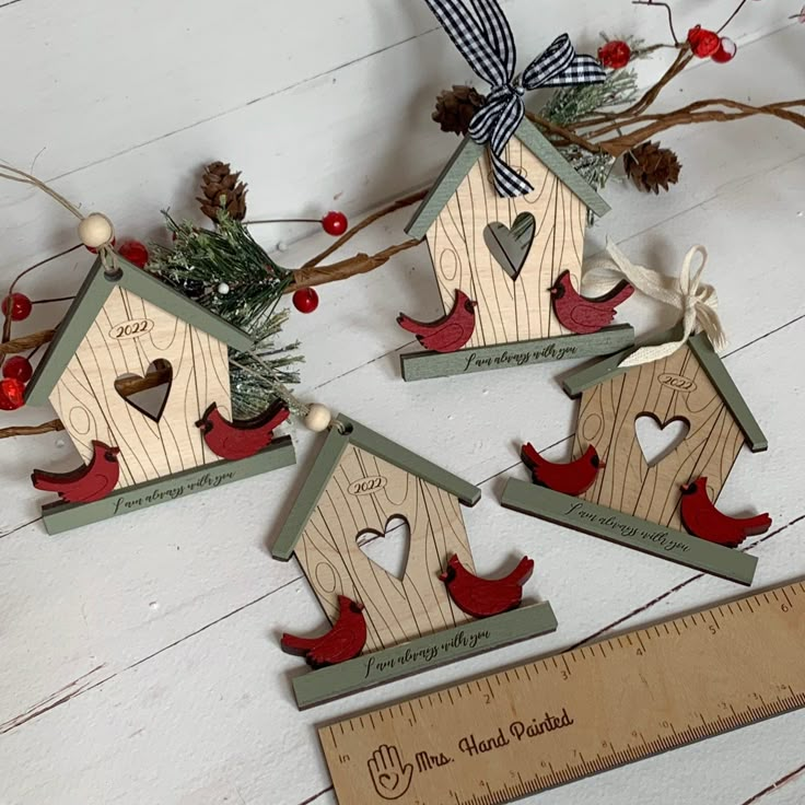 three wooden birdhouses with birds on them next to a ruler and christmas tree branch