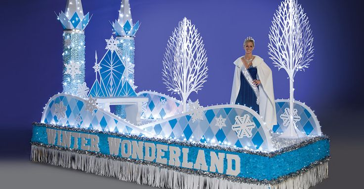 a man dressed in white and blue stands on top of an ice sculpture with snowflakes