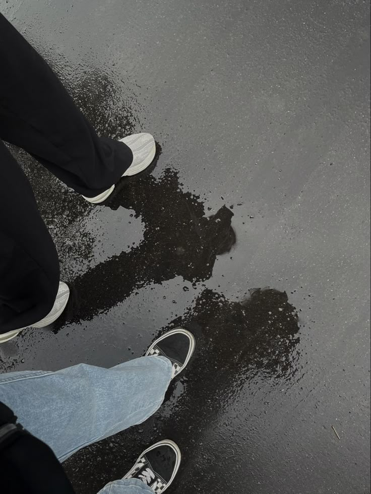 two people standing in the rain with their shoes on