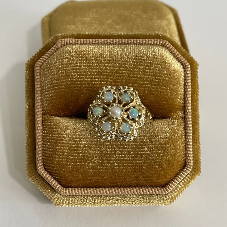 "Gorgeous vintage 14k yellow gold genuine opal & seed pearl cluster ring! This stunning retro piece features one genuine seed pearl center stone, surrounded by a halo of six genuine .66 ctw opal gems . The opals display a vibrant play-of-color, flashing orange, green, & violet hues. Lovely retro statement piece of fine jewelry circa 1970s, featuring October's birthstone!  ERA - Circa 1970s, Retro Era  METAL / MATERIAL - 14k yellow gold, 1 genuine seed  pearl , 6 genuine round cut opals ( approx. .66 CTW ) MARKINGS / HISTORY - Inside band is marked \"14k\" Skal SIZE / MEASUREMENTS - Size: 7.5, Ring Head Height: 14.2 mm, Rise off finger: 9.4 mm,Back of shank: 1.2 mm,Ring Weight: 4.98grams https://www.etsy.com/shop/LastCenturyJewels" Pearl Halo Ring, Gem Cluster, Pearl Cluster Ring, Retro Era, Gold Rings Jewelry, Pearl Cluster, Jewelry Lookbook, Wedding Rings Vintage, October Birthstone