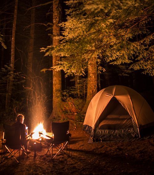 a man sitting in front of a campfire next to a tent with the words boa noite on it