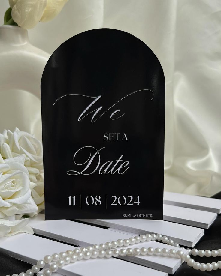 a black and white save the date card with pearls on it next to a bouquet of flowers