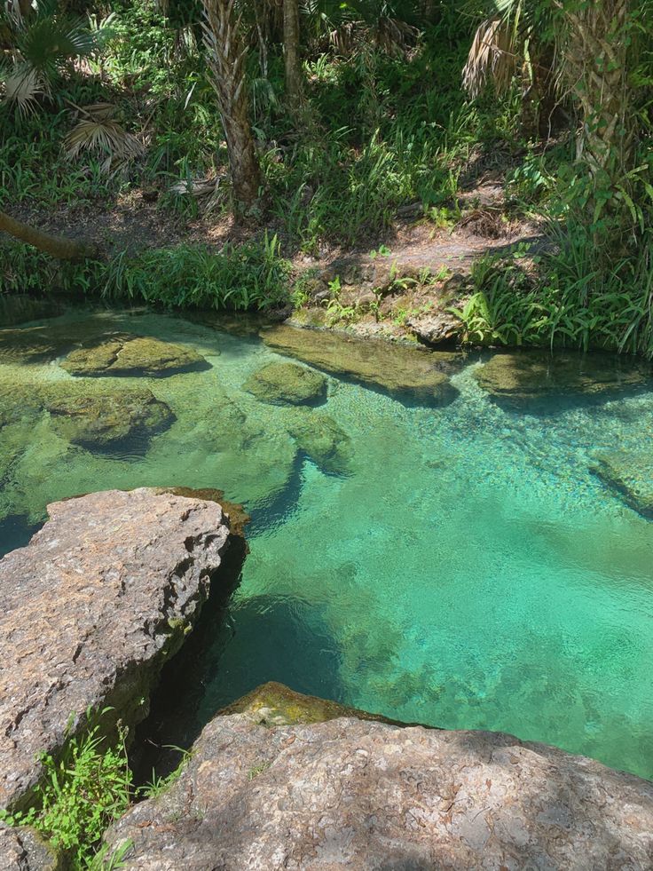 the water is crystal green and blue in this river bed, surrounded by large rocks