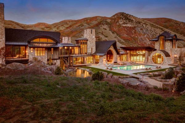 a large house with a pool in the middle of it's yard, surrounded by mountains