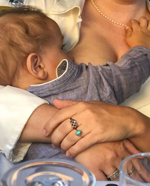 a woman holding a baby in her arms and wearing pearls on it's head