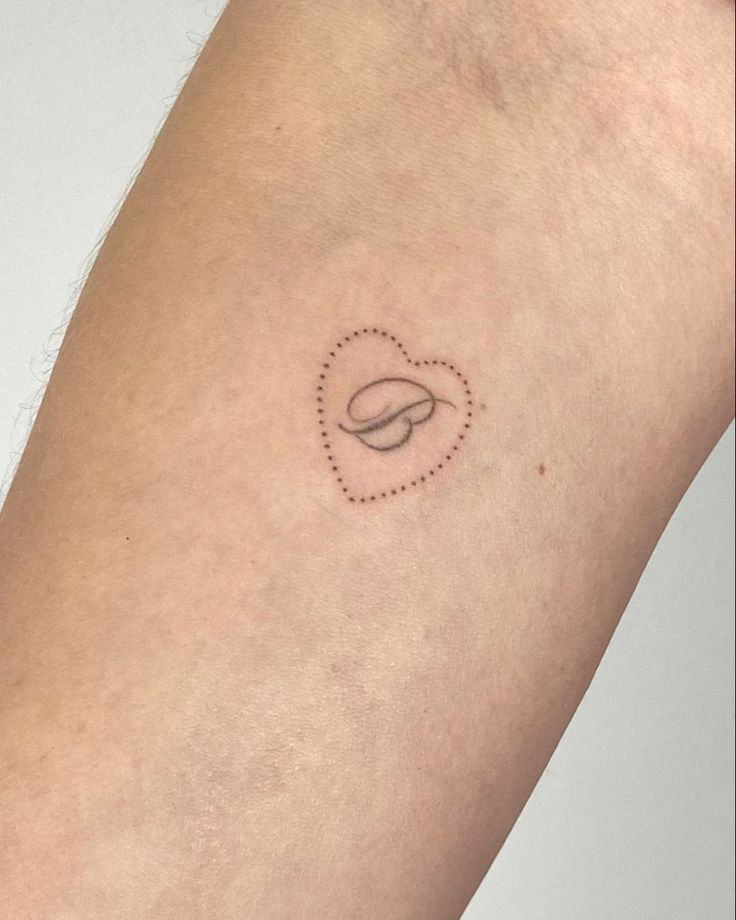 a small tattoo on the arm of a woman with a heart shaped object in it