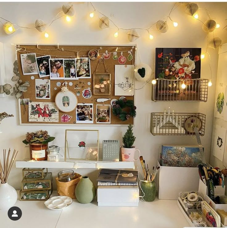 a desk with many pictures on the wall and lights strung above it, along with other office supplies