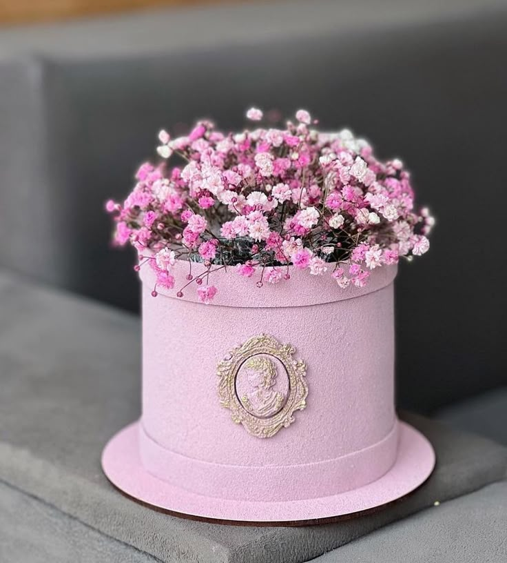 a pink hat with flowers in it sitting on a table next to a gray couch