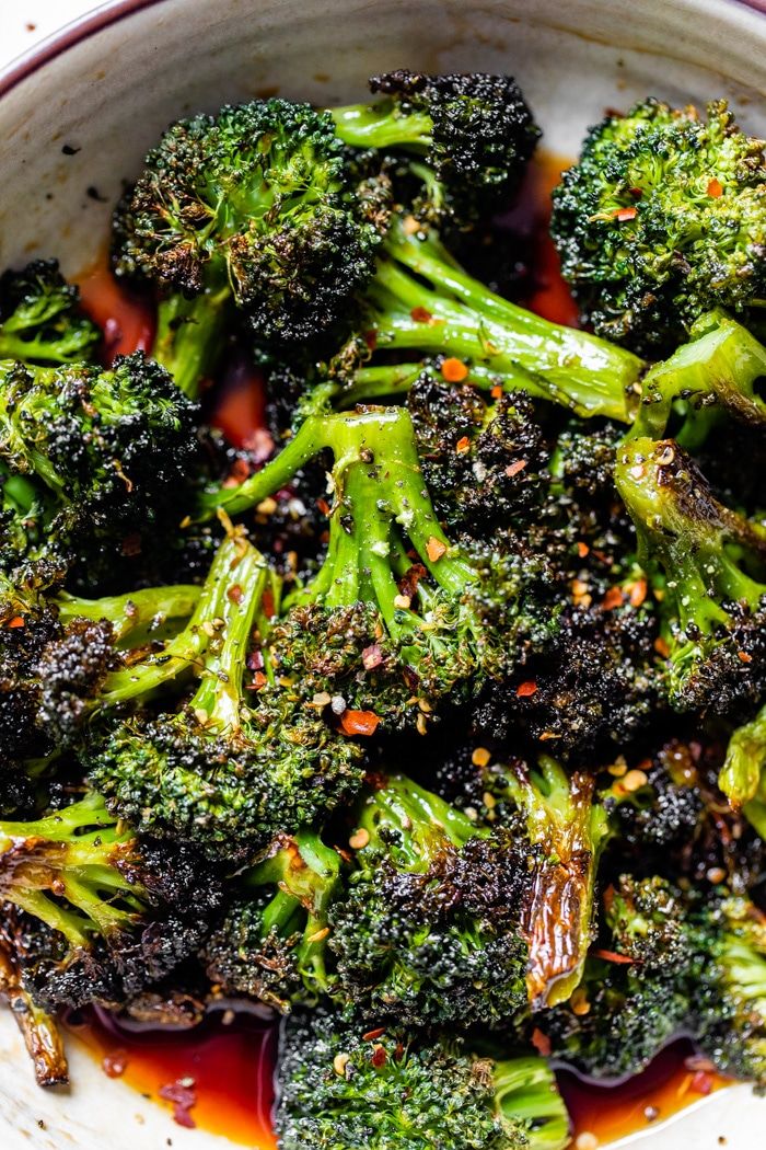 broccoli florets with red sauce in a white bowl