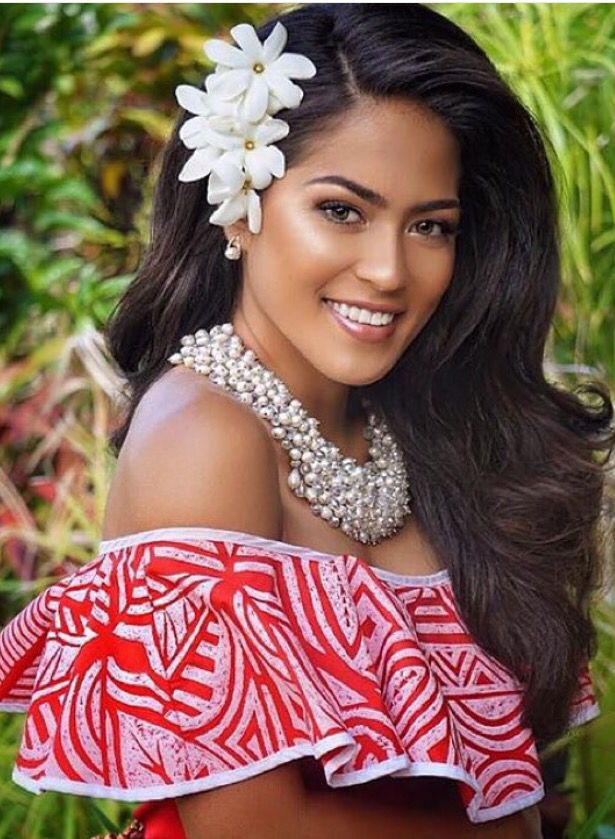 a woman wearing a red and white dress with flowers in her hair smiling at the camera