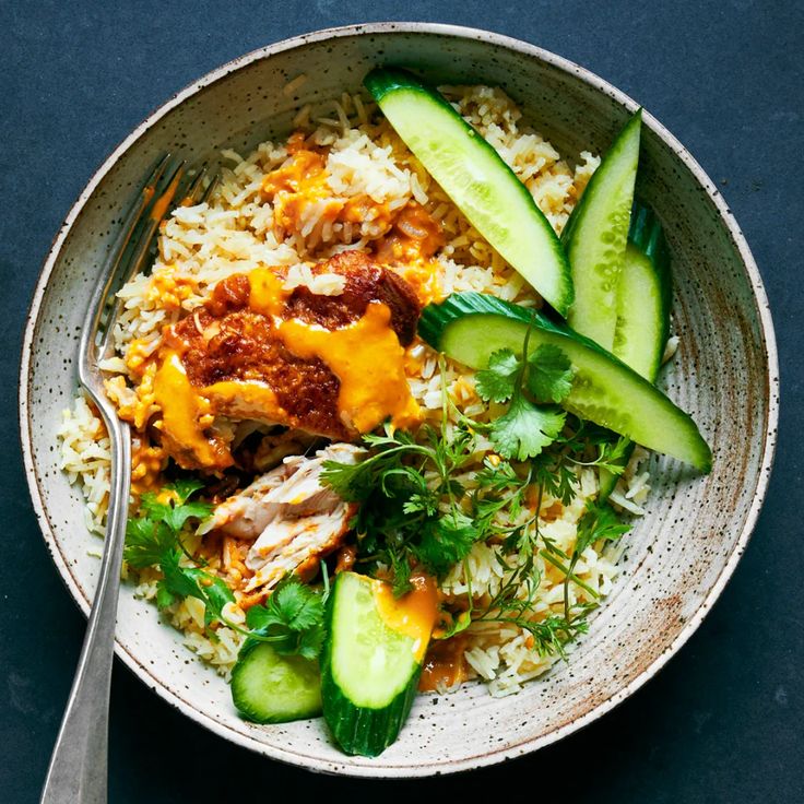 a bowl filled with rice, cucumbers and meat