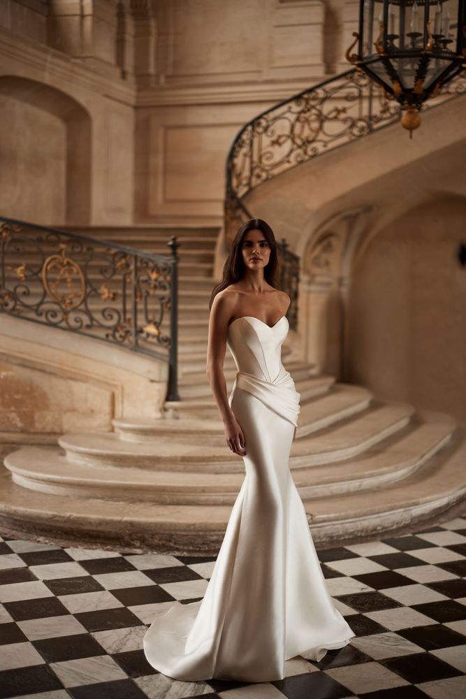 a woman in a white dress standing on a checkered floor next to a staircase