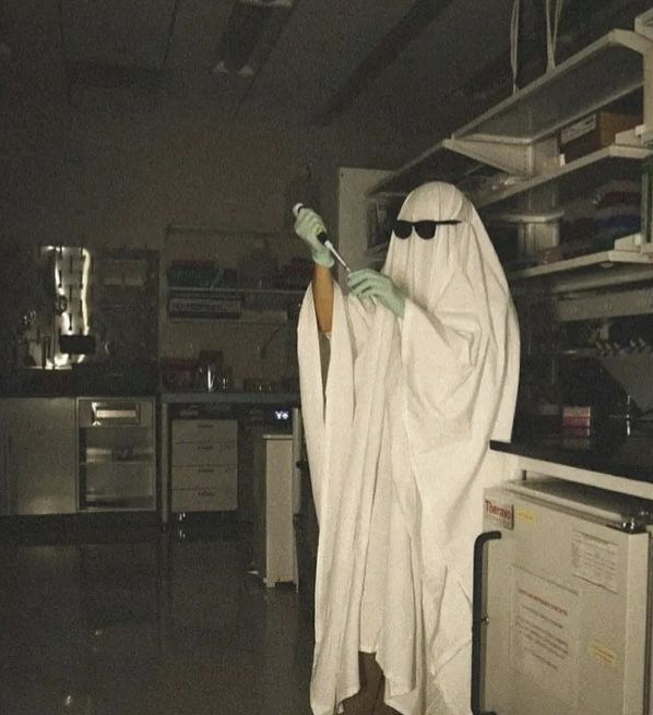 a person dressed as a ghost holding a toothbrush in their hand and standing next to an oven