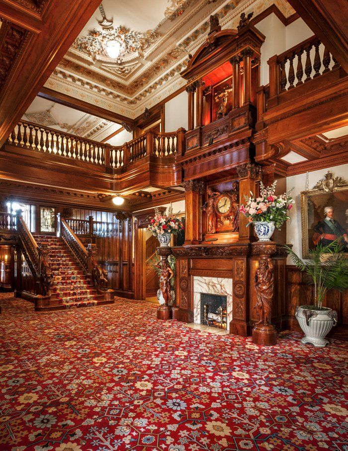 an ornately decorated living room with red carpet and wooden staircase leading up to the second floor