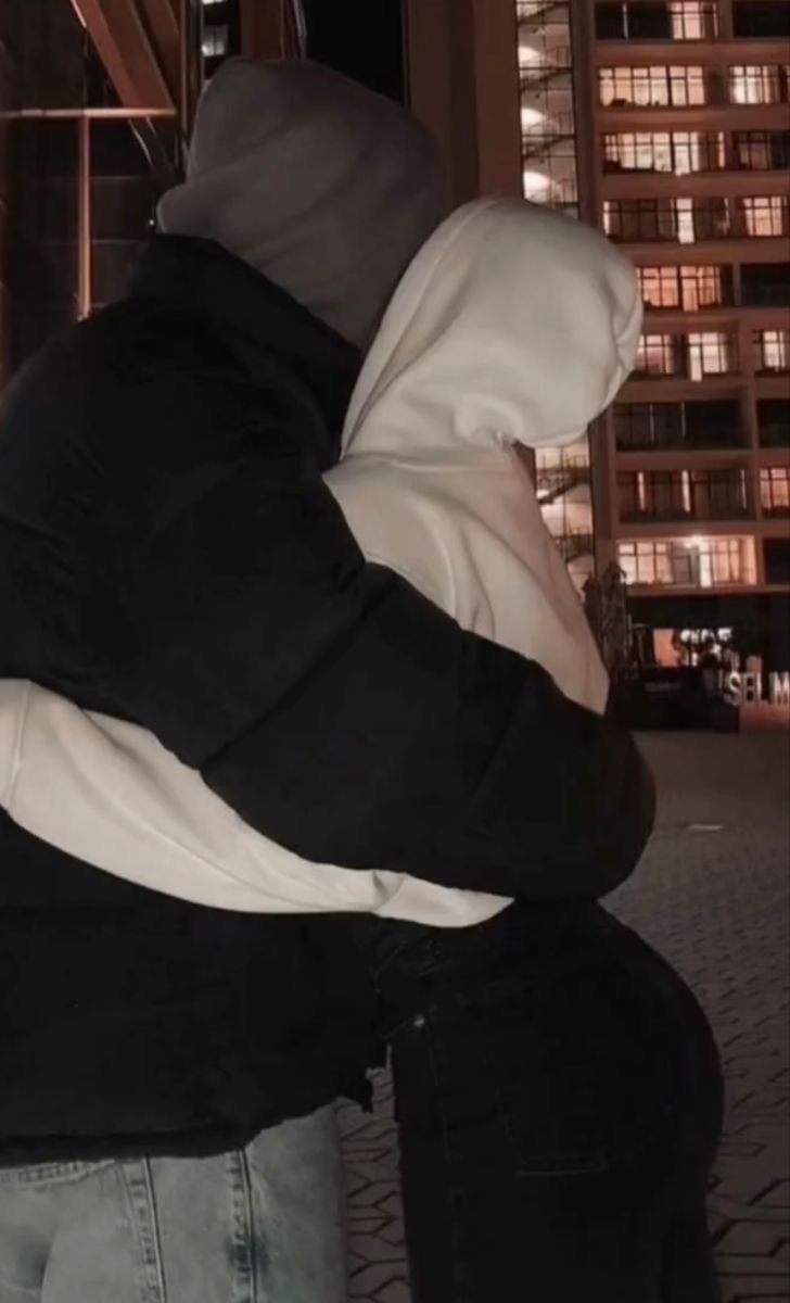 a person sitting on a bench in front of a building at night with their back to the camera