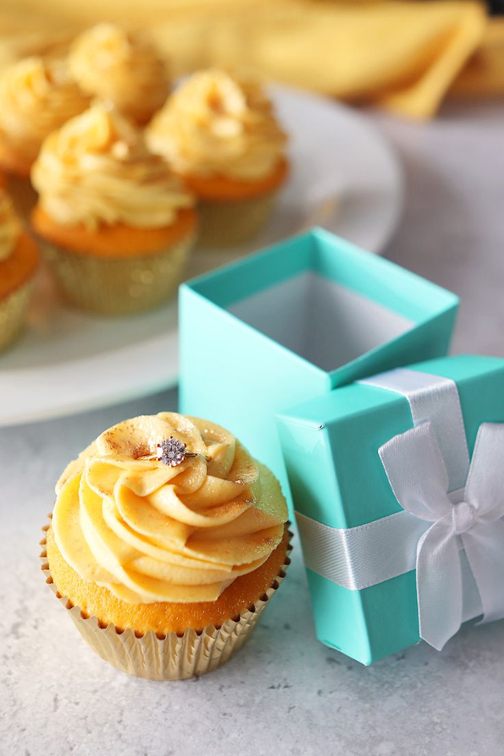 cupcakes with frosting in blue boxes next to each other on a table