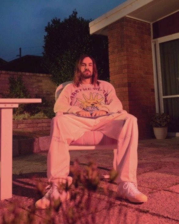 a man with long hair sitting on a bench in front of a house at night