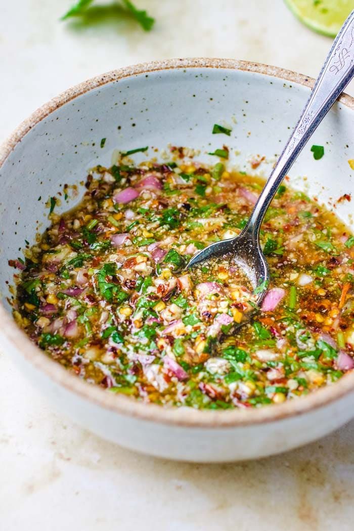 a white bowl filled with food next to a spoon and some limes on the side