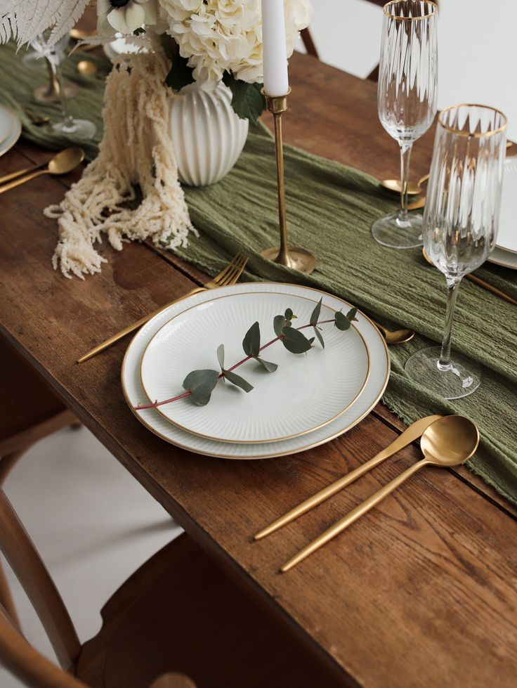 the table is set with white flowers and goldware