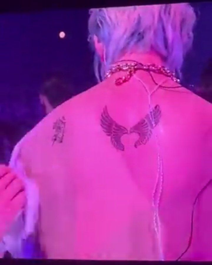 the back of a woman's pink shirt with an eagle tattoo on her left shoulder