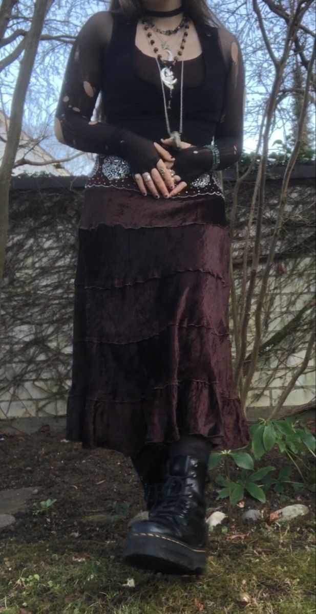 A mid-size person/girl wearing mate rose lipstik, a black tight waistcoat with a ripped stocking selfmade longsleeve and a thrifted dark brown maxi skirt, black dr. Martins and multiple crystal rings and bracelets. 	The person is also wearing multiple silver necklaces, one in form of a dragonfly and another in form of a moon, a green crystal bead necklace and a black lace choker. Fairy Goth Outfit, Fit Aesthetic Outfit, Goblin Forest, Grunge Fairycore Outfits, Dryad Costume, Ripped Stockings, Grunge Plus Size, Fem Style, Fairy Grunge Outfit