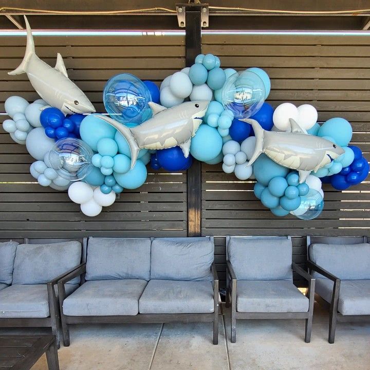 some chairs and balloons are in front of a wall with dolphins on it, one dolphin is jumping out of the water