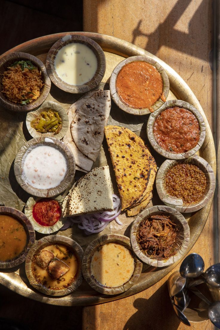 an overhead view of several different types of food on a wooden tray with spoons