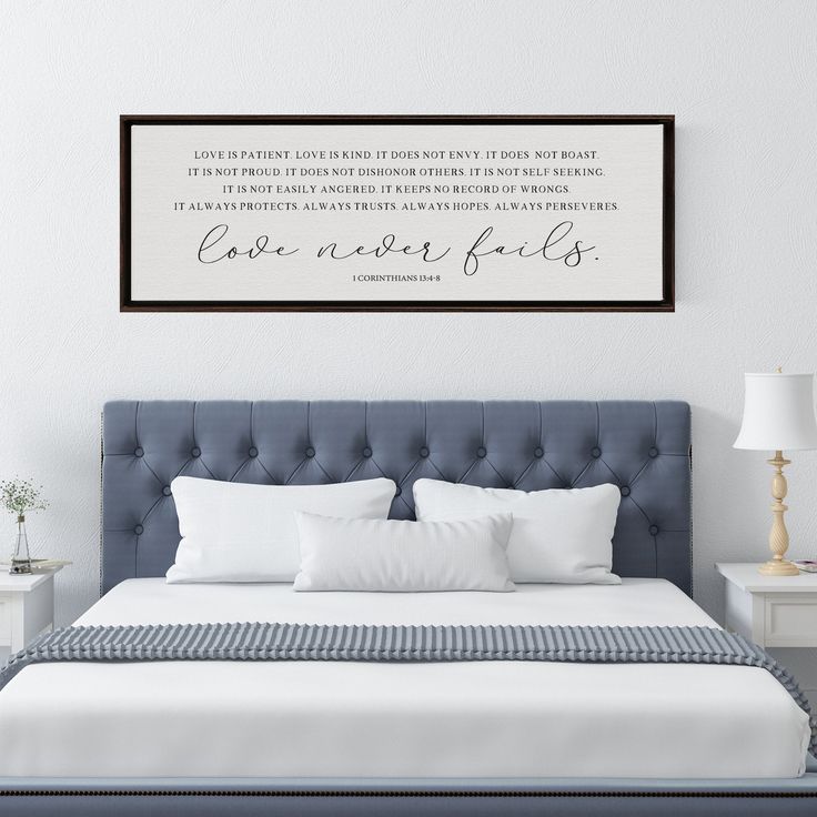 a bedroom with a bed, night stand and framed wall art above it that says love never ends