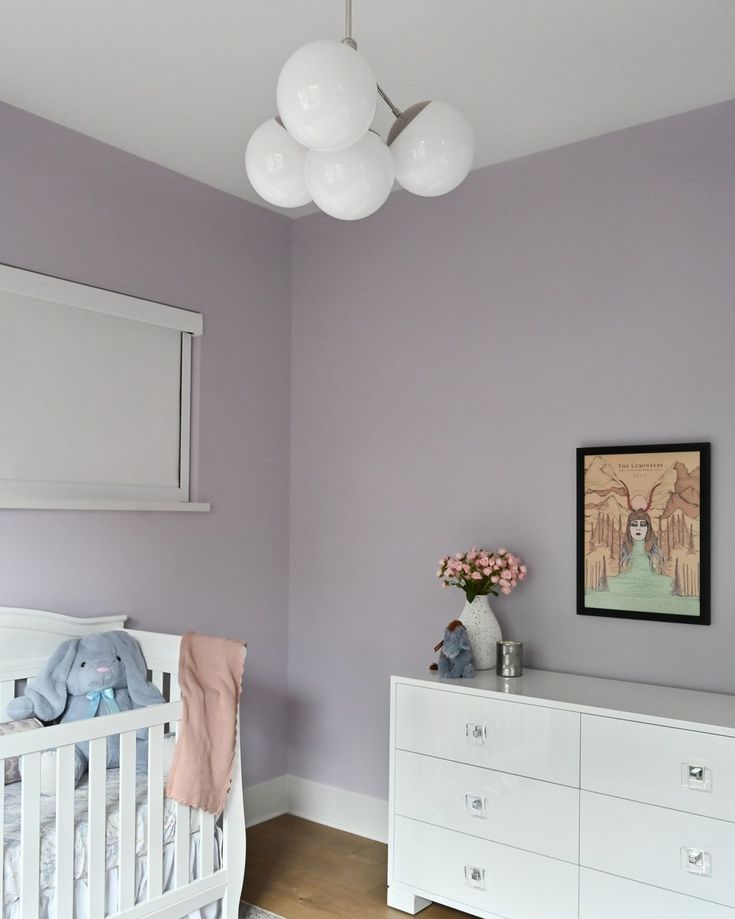 a baby's room with purple walls and white furniture