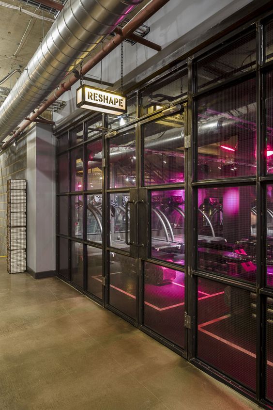 the inside of a building with lots of glass doors and pink lights on it's windows