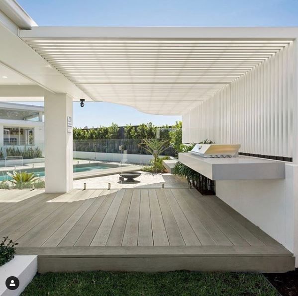 an outdoor bathroom with wooden floors and white walls, next to a swimming pool in the back yard