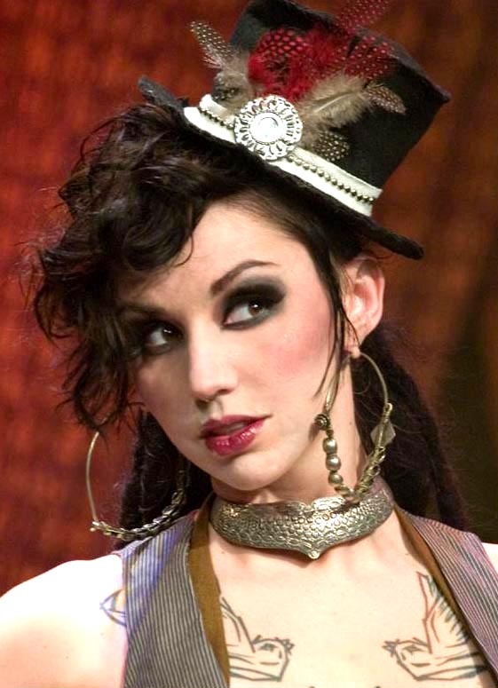 a woman wearing a top hat with feathers on it's head and necklaces around her neck